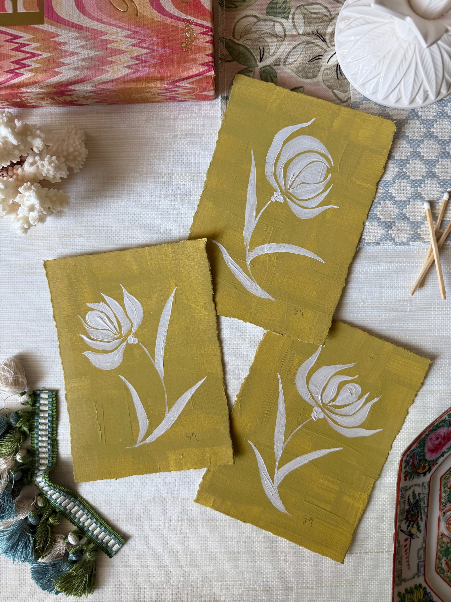 Three green fabric squares with white floral patterns on a textured surface.
